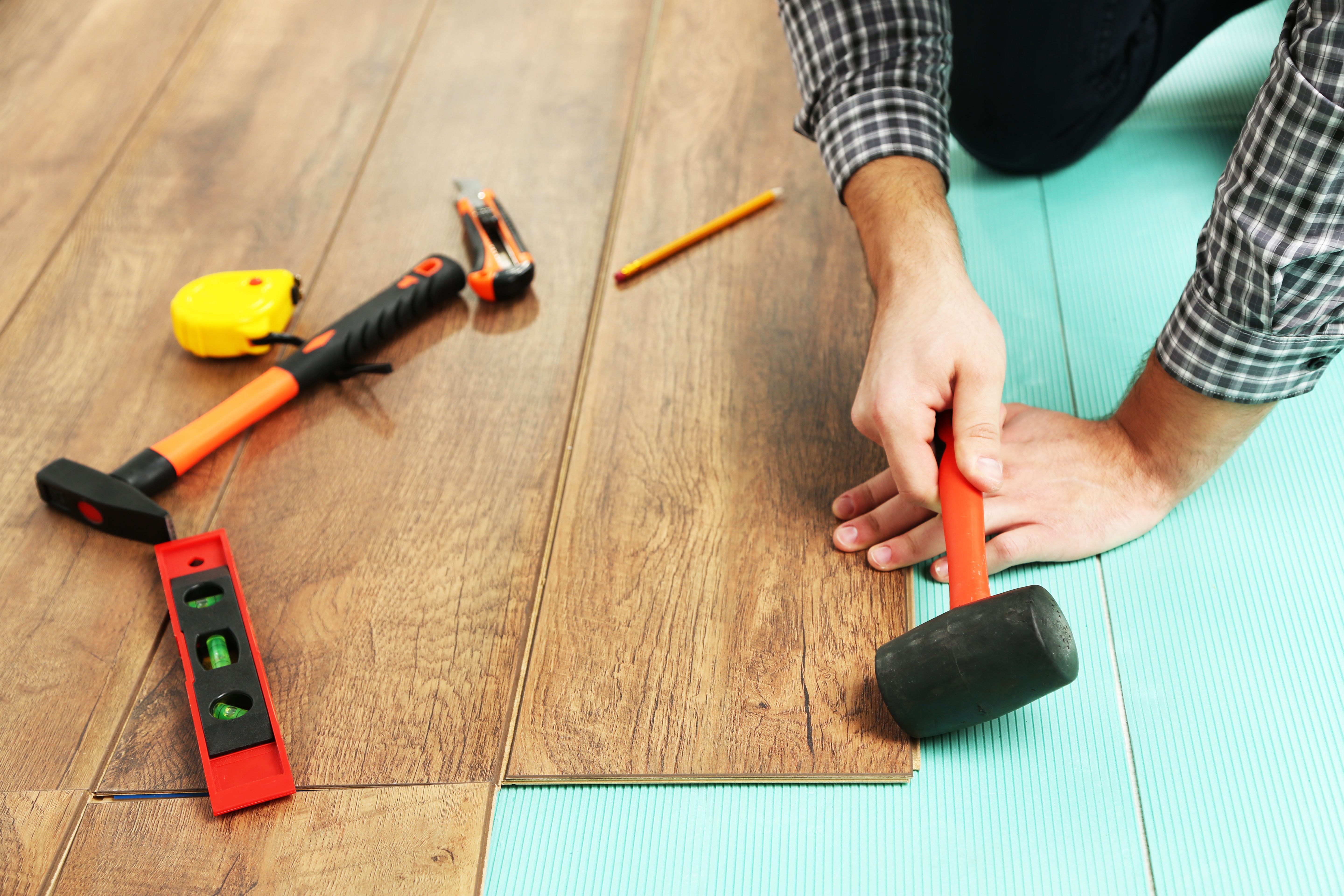 Installer laying vinyl plank flooring.